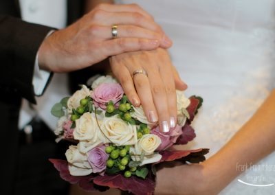 Brautpaar mit angesteckten Eheringen über Brautstrauss